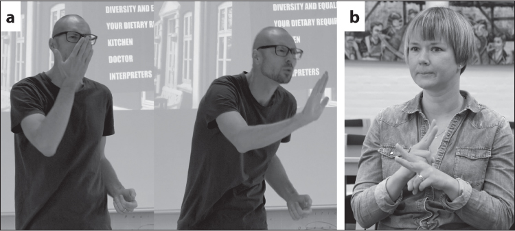 a) 1) A bald white man in a T-shirt and glasses is standing in front of a PowerPoint presentation; the text on the screen behind him reads “diversity and equality; your dietary requirement; kitchen; doctor; interpreters”.. He is signing with his hand up to his face, his palm facing his nose. 2) He leans forward, his palm now facing away from him, hand moving towards the audience. b) A white woman with short, straight blonde hair wearing a denim shirt is signing with her right fist resting on top of her left fist in front of her body, the index and middle fingers of each hand extended.
