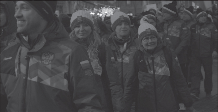 A large group of white people in ski jackets and winter hats (Russian) walking together.