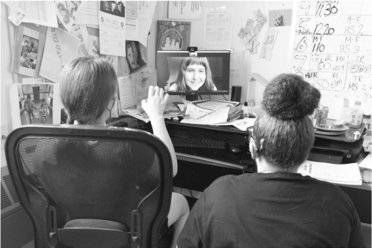 Students on a video call with a woman on the screen.