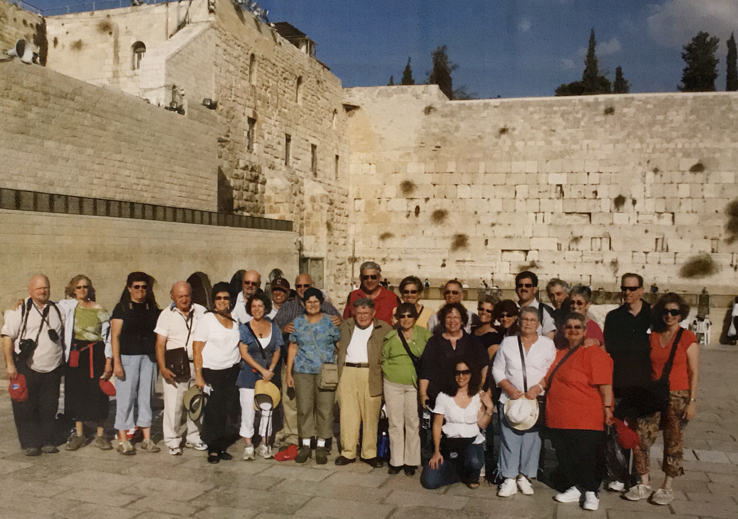 A group of white tourists stand in front of the Western wall in Jerusalem.