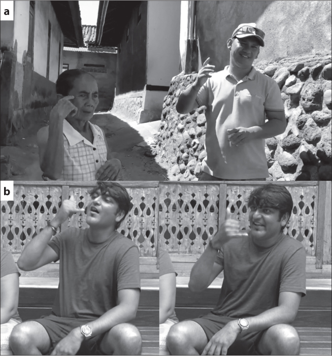 a) Wayhu, a young Balinese man wearing a brightly coloured T-shirt and a baseball hat with sunglasses balanced on the rim, is standing outside in a narrow street between stone houses, grinning at the camera, his right hand raised. Beside him is a small, elderly Balinese woman in a checked sundress. She is signing with her right hand raised to her face, her wrist bent, and her index finger touching her temple. Caption reads ““deaf” (Kata Kolok)”. b) Harish, a young Indian man in shorts and a T-shirt, is smiling and signing, his right fist beside his face, index and little finger extended.