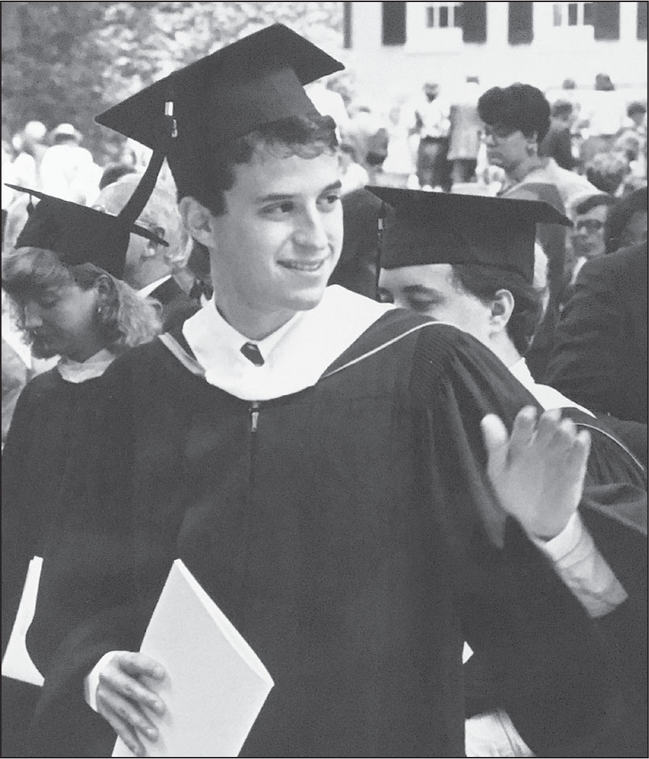 A black-and-white photo of a young man in a robe and mortar board. He's looking over his shoulder with one hand raised.