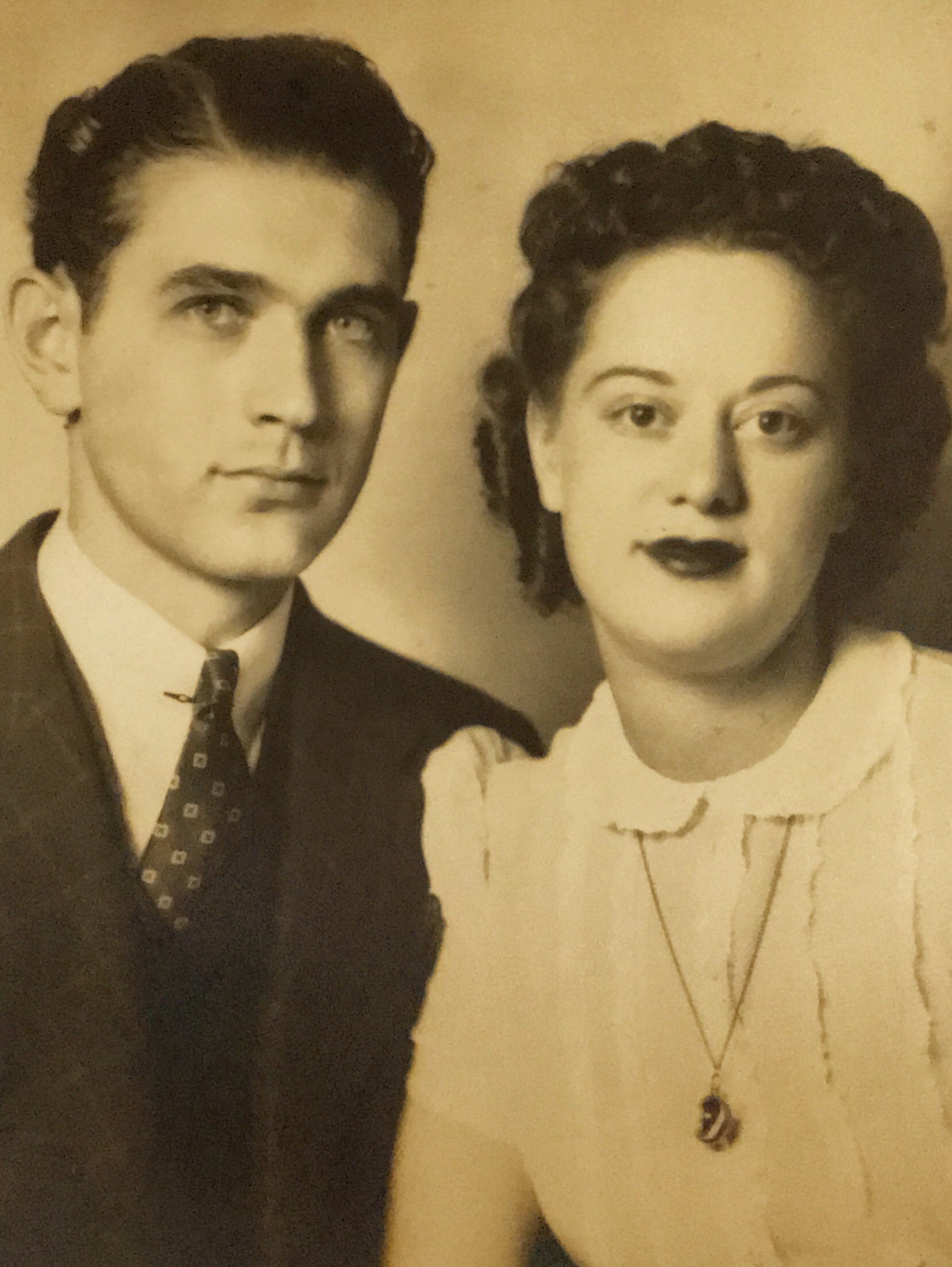 A sepia colored photo of a young, clean shaven white man in a suit and tie and a young white woman with wavy hair wearing a light-colored blouse with a Peter Pan collar