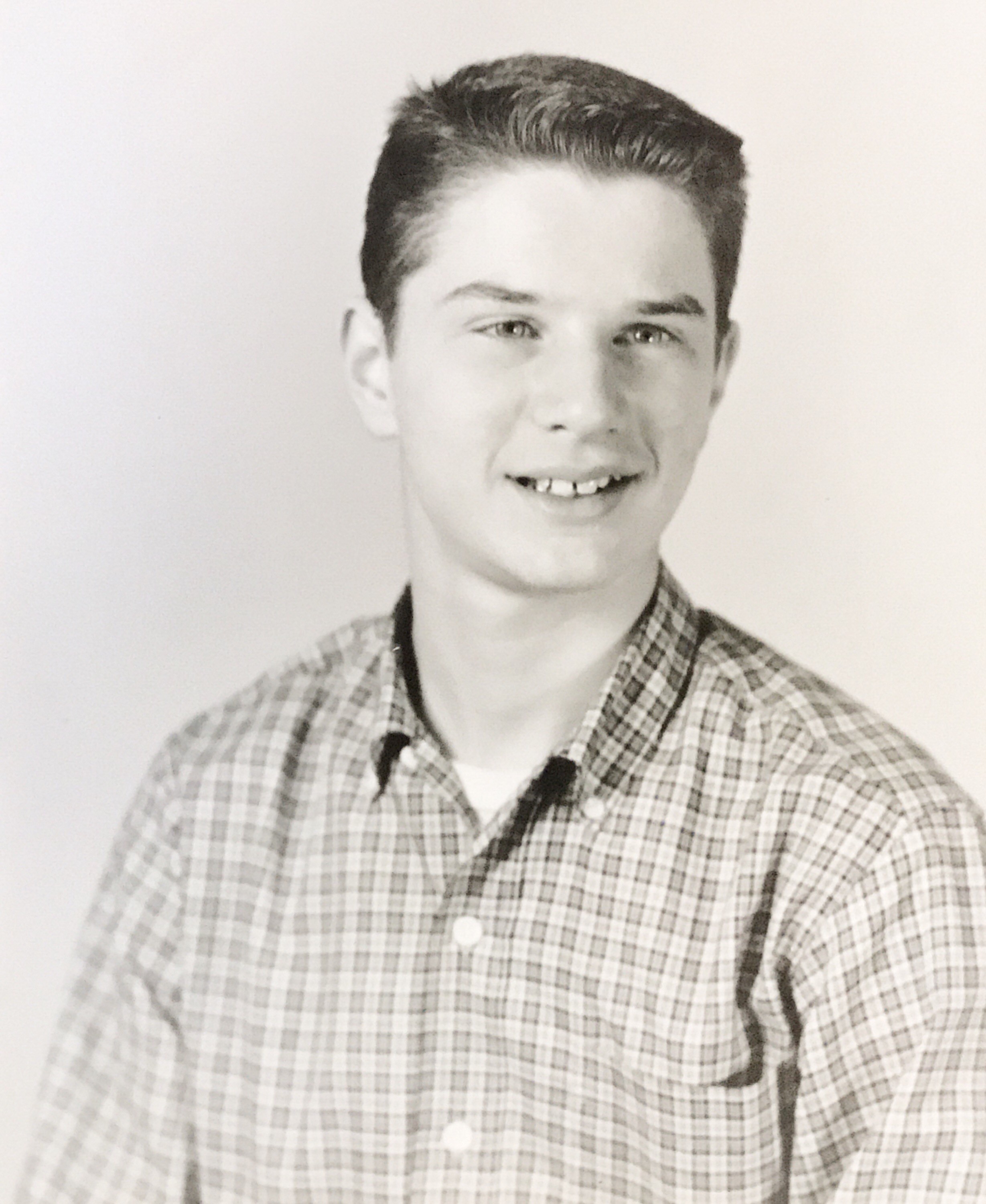 Black-and-white photo of a young white male teenager with a crew cut. He's wearing a checked shirt and is looking to the right of the camera.
